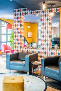 a lobby with two blue couches and a mirror at ibis Styles Reims Centre in Reims