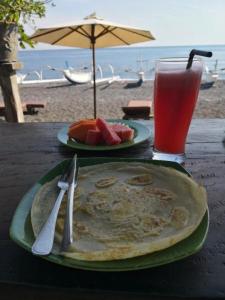 ein Tisch mit zwei Tellern Essen und einem Getränk in der Unterkunft Putra'Lebah Amed Guest House in Amed + 37 Fotos