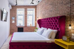 a bedroom with a red headboard and a brick wall at KievApts Maydan Apartments in Kyiv