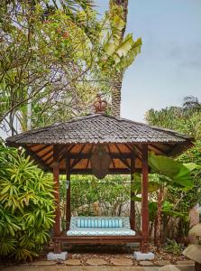 a wooden gazebo with benches in a garden at The Ocean Club, A Four Seasons Resort, Bahamas in Nassau