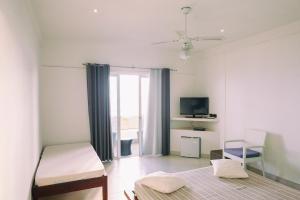 a white room with a bed and a tv at Etoile Blanche in Nosy Be