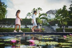a man and a woman walking by a pond of water lilies at The Ocean Club, A Four Seasons Resort, Bahamas in Nassau