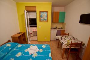 a small room with a bed and a table and a kitchen at Apartmani HRGA in Vodice