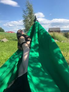 a woman is laying in a green hammock at SAGA, badehotell med sauna og badebrygge - Inderøy in Straumen