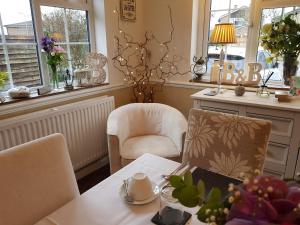 een eetkamer met een tafel, stoelen en ramen bij Wisteria Haze in Cranfield