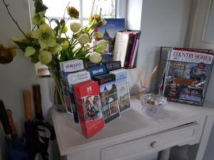 een tafel met boeken en een vaas met bloemen erop bij Wisteria Haze in Cranfield