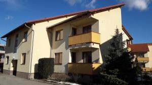 a white building with a tree in front of it at ÉKKŐ APARTMAN in Hegykő