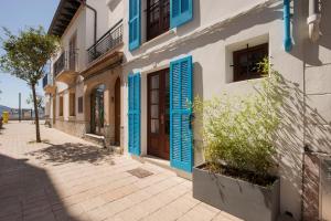 a street with blue shutters on a building at Villa Ca na Magdalena - La Goleta Hotel de Mar & Villas in Port de Pollensa