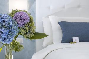 un jarrón lleno de flores moradas y azules junto a una cama en St. Peter Fortytwo, en Roma 43 fotos más