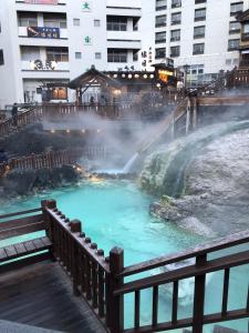a hot tub with a waterfall in a city at Oyado Zen in Kusatsu