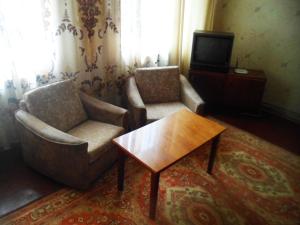 uma sala de estar com duas cadeiras e uma mesa e uma televisão em Дом em Okhtyrka
