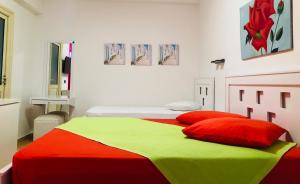a bedroom with two beds with red and green sheets at Envi Hotel in Vlorë