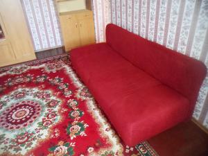 um sofá vermelho num quarto com um tapete vermelho em Дом em Okhtyrka