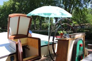 ein Boot mit einem Regenschirm und einem Stuhl auf einem Boot in der Unterkunft studio sur péniche La Tortue in Ramonville-Saint-Agne