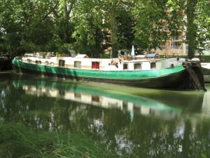 una barca è ormeggiata su un fiume con il suo riflesso di studio sur péniche La Tortue a Ramonville-Saint-Agne