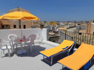 einen Balkon mit einem Tisch, Stühlen und einem Sonnenschirm in der Unterkunft Azzurromare Apartment in Syrakus