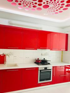 a red kitchen with white counters and red cabinets at Ogienka 2b, Center Lutsk in Lutsk