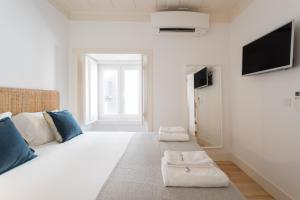 - une chambre blanche avec un grand lit et une télévision dans l'établissement FLH Anjos Lovely Apartment, à Lisbonne