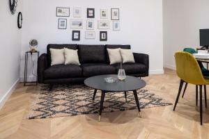 a living room with a black couch and a table at Hypercentre Charmant 2 Chambres Au Calme avec Joli Patio Privatif in Nantes