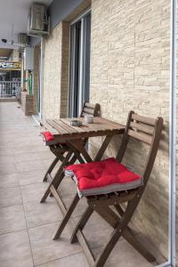 Drewniany stół piknikowy z czerwonymi poduszkami na patio w obiekcie Behome 37 w Salonikach