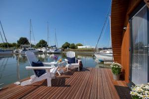 two chairs and a table on a dock with boats at Sea Breeze Ark 900 in Emsworth