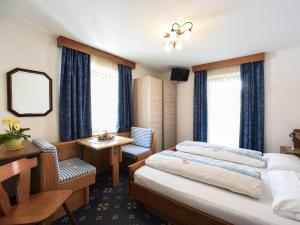 um quarto de hotel com duas camas e uma mesa e uma secretária em Garní Emma em Arabba