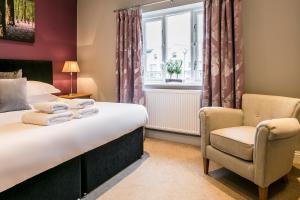 a bedroom with a bed and a chair and a window at The Lodge @ Carus Green in Kendal +35 photos