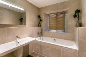 a bathroom with a tub and a sink and a mirror at The Lodge @ Carus Green in Kendal