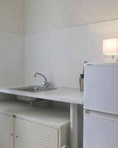 a white kitchen with a sink and a refrigerator at Mini Loft Del Sarte CityCosy in Paris