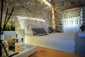 a bedroom with a white bed and a stone wall at Paxos Fairytales Lovenest 2 in Gaios