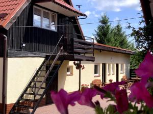 un edificio con una escalera y flores púrpuras en Pensjonat U Kasi en Węgorzewo