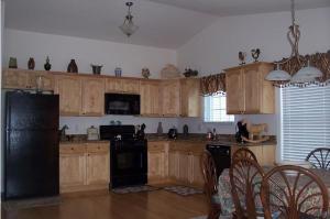 uma cozinha com armários de madeira e um frigorífico preto em Fountain Motel Townhouse with Shared Pool em Wildwood