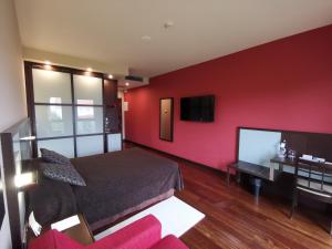 a bedroom with a red wall with a bed and a tv at Royal Nayef in Portonovo