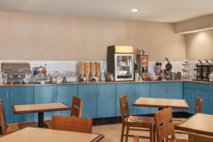 un restaurante con armarios azules y mesas de madera en Country Inn & Suites by Radisson, Buffalo, MN, en Buffalo