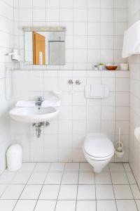 a white bathroom with a toilet and a sink at Gasthof Metzgerei Neumeyer in Kipfenberg