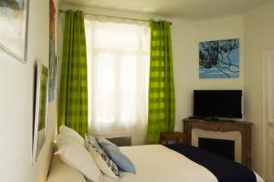 een slaapkamer met een bed en een raam met groene gordijnen bij CANNES - À DEUX PAS DU PALAIS DES FESTIVALS in Cannes