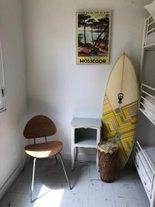 a room with a surfboard and a chair and a table at Surfhostel Hossegor in Soorts-Hossegor