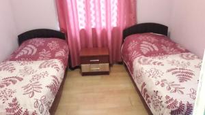 two beds in a small room with pink curtains at kobuleti bagrationi 40 in Kobuleti