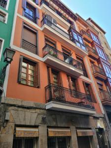 un edificio naranja con balcones en una calle en Apartamento turistíco Casco viejo tradición pinchos y gastronomía en Bilbao