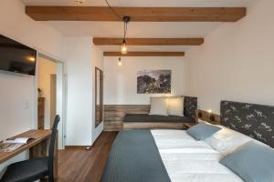 - une chambre avec un lit, un bureau et un canapé dans l'établissement Das Talblick - Appartments, à Sankt Johann im Pongau