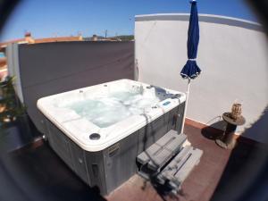 Nueva suite jacuzzi relax beach & mountain في بالاموس: حوض استحمام ساخن فوق مبنى به مظلة