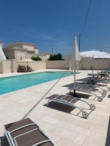 a row of lounge chairs and umbrellas next to a swimming pool at Le Terrazze Miramare B&B in Torre Canne