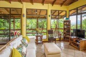 a living room with a couch and a tv at Kiskadee Casa in Quepos