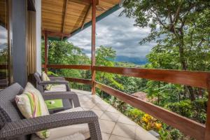 balcón con sillas y vistas al bosque en Kiskadee Casa, en Quepos