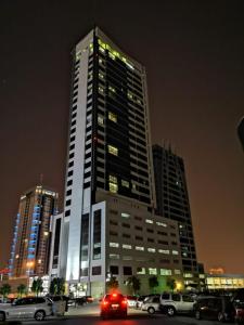 a tall building with cars parked in a parking lot at S Hotel Bahrain in Manama