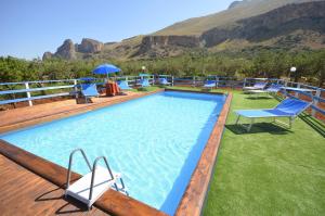 a large swimming pool on a deck with mountains in the background at B&B Maria Paola in Castelluzzo