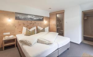 ein Schlafzimmer mit einem großen Bett mit weißer Bettwäsche und Kissen in der Unterkunft Garni Ötztal ROOMS & APARTS in Sölden