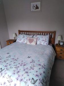 a bedroom with a bed with purple flowers and butterflies at The Boyne Arms in Burwarton