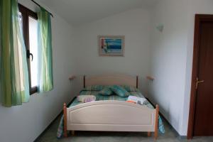 małe łóżko w białym pokoju z oknem w obiekcie Agriturismo B&B Casteldoria w mieście Santa Maria