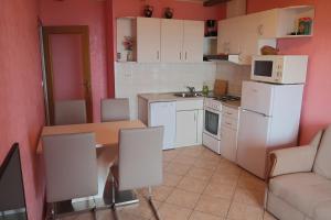 una cocina con electrodomésticos blancos y una mesa con sillas. en Guest house Ivo, en Lovran